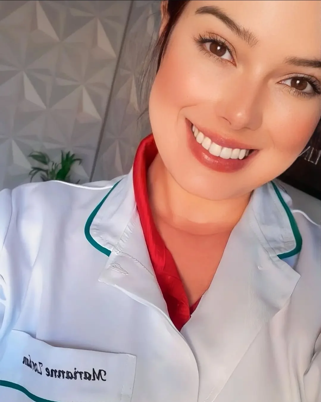 Marianne Zordan sorrindo, de jaleco branco com o nome bordado